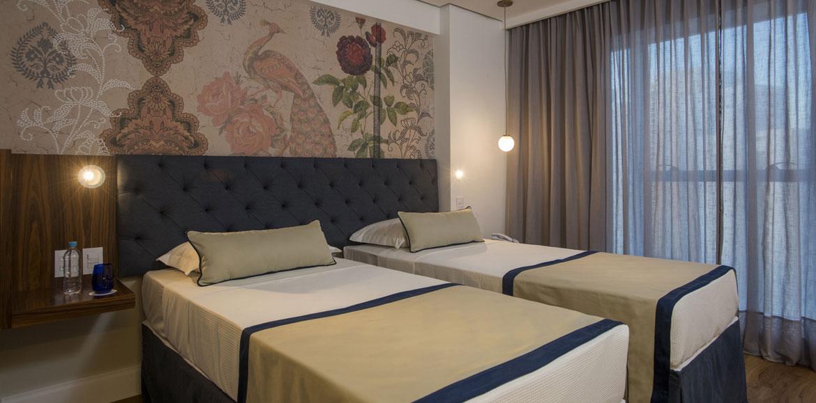 Hotel Luzeiros 헤시피 외부 사진 The photo shows a modern bedroom featuring two single beds that are neatly made with light-colored blankets and decorative pillows. The headboard of the beds is upholstered in a dark material, giving it a stylish appearance. Behind the beds, there is
